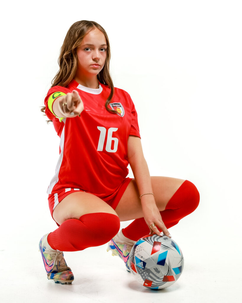 Olivia Leddy with a soccer ball pointing her finger